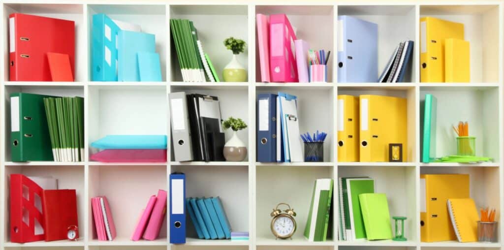 Color coordinated folders on a book shelf.